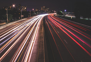 Carros em alta velocidade na rodovia, deixando um caminho de luz